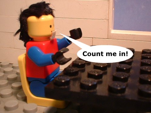 A Lego figure sitting on top of a black Lego table. The figure is wearing a red and blue outfit with black hair and is holding a pair of scissors in its right hand. The text on the image reads "Count me in!"