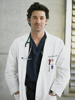 A portrait of a man wearing a white lab coat and a stethoscope around his neck. He is standing in front of a white wall with a window on the right side. The man has dark hair and is looking directly at the camera with a slight smile on his face. He has a name tag attached to his coat with the words "Dr. David Shrigley" written on it. He appears to be a medical professional or a doctor.