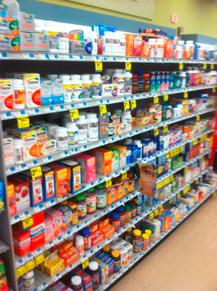 A supermarket aisle with multiple shelves stocked with various products. The shelves are arranged in a grid-like pattern and are filled with different types of food and drinks. On the left side of the aisle there are boxes of milk yogurt and other dairy products while on the right side there is a carton of milk. The products are neatly arranged on the shelves and are labeled with yellow price tags. The aisle appears to be well-stocked and well-organized.