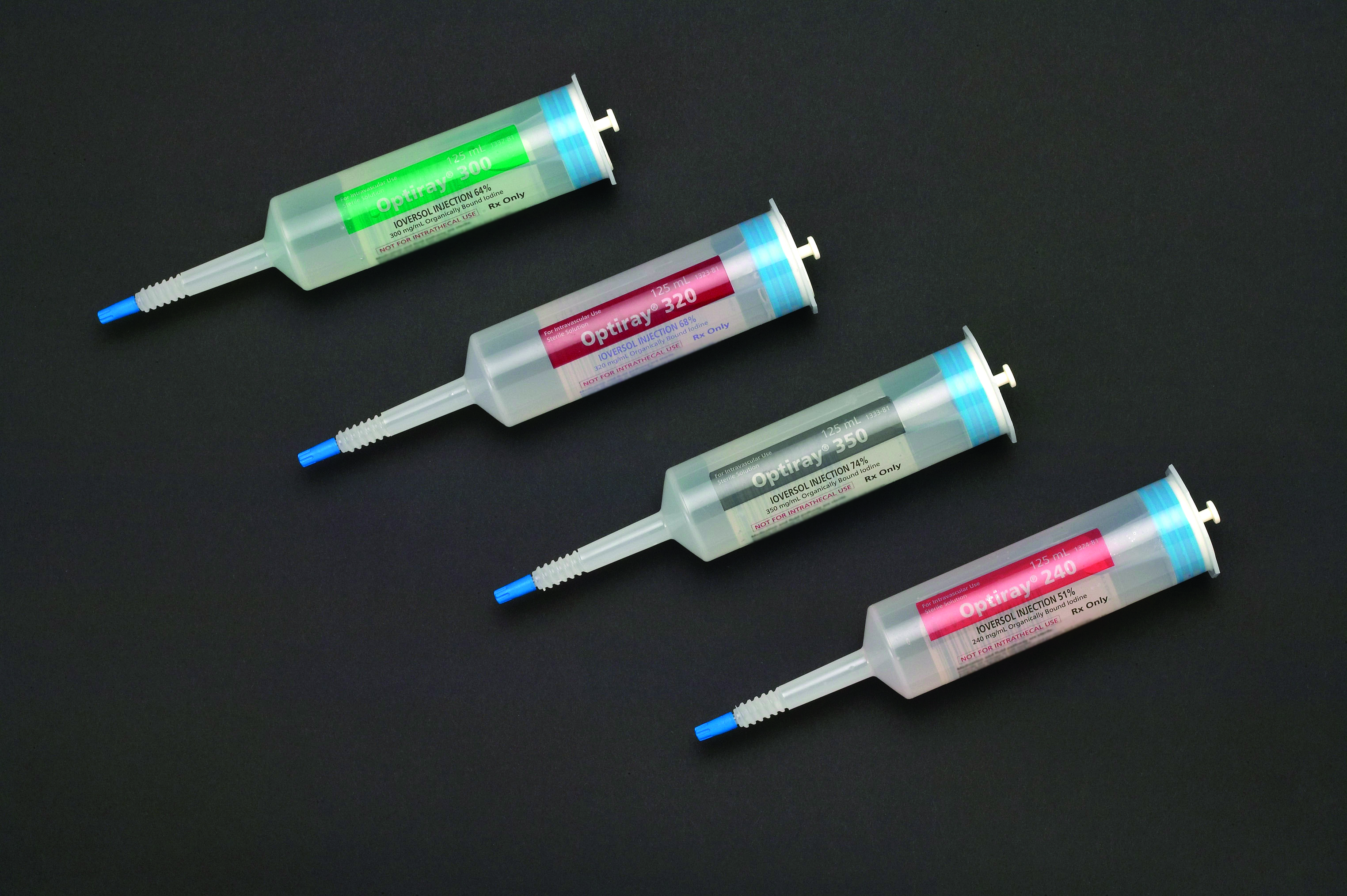 Four syringes of different sizes and colors - green blue and pink - arranged in a row on a black background. Each syringe has a blue needle and a white cap. The syringe is labeled with the brand name "Ophthalmoscope" and the size of the needle is 250ml. The needles appear to be new and unused. The background is plain black making the syringe stand out.