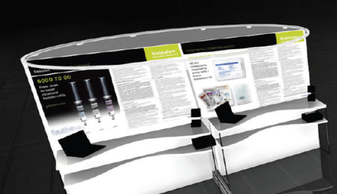 A 3D rendering of a trade show booth. The booth is white with a curved design and has a black and yellow banner at the top. The banner has the words "Good to go" written in bold black letters. Below the banner there is an image of three syringes with different sizes and colors. On the right side of the booth there are several pages of information about the product including a website and a contact form. The background is black and the booth is standing on a black floor.