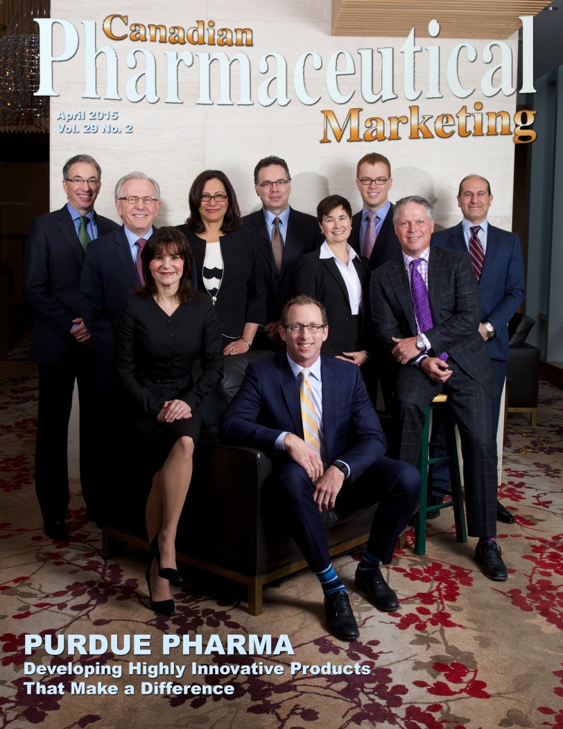 A cover of a magazine titled "Canadian Pharmaceutical Marketing" from April 2015. It features a  photo of a group of people. The group is composed of ten people six men and three women all dressed in formal business attire. They are all smiling and looking at the camera. The background appears to be a large room with a high ceiling and a chandelier hanging from the ceiling.  The cover features an article title: "Purdue Pharma: Developing Highly Innovative Products That Make a Difference". The overall theme of the photo is professional and modern.