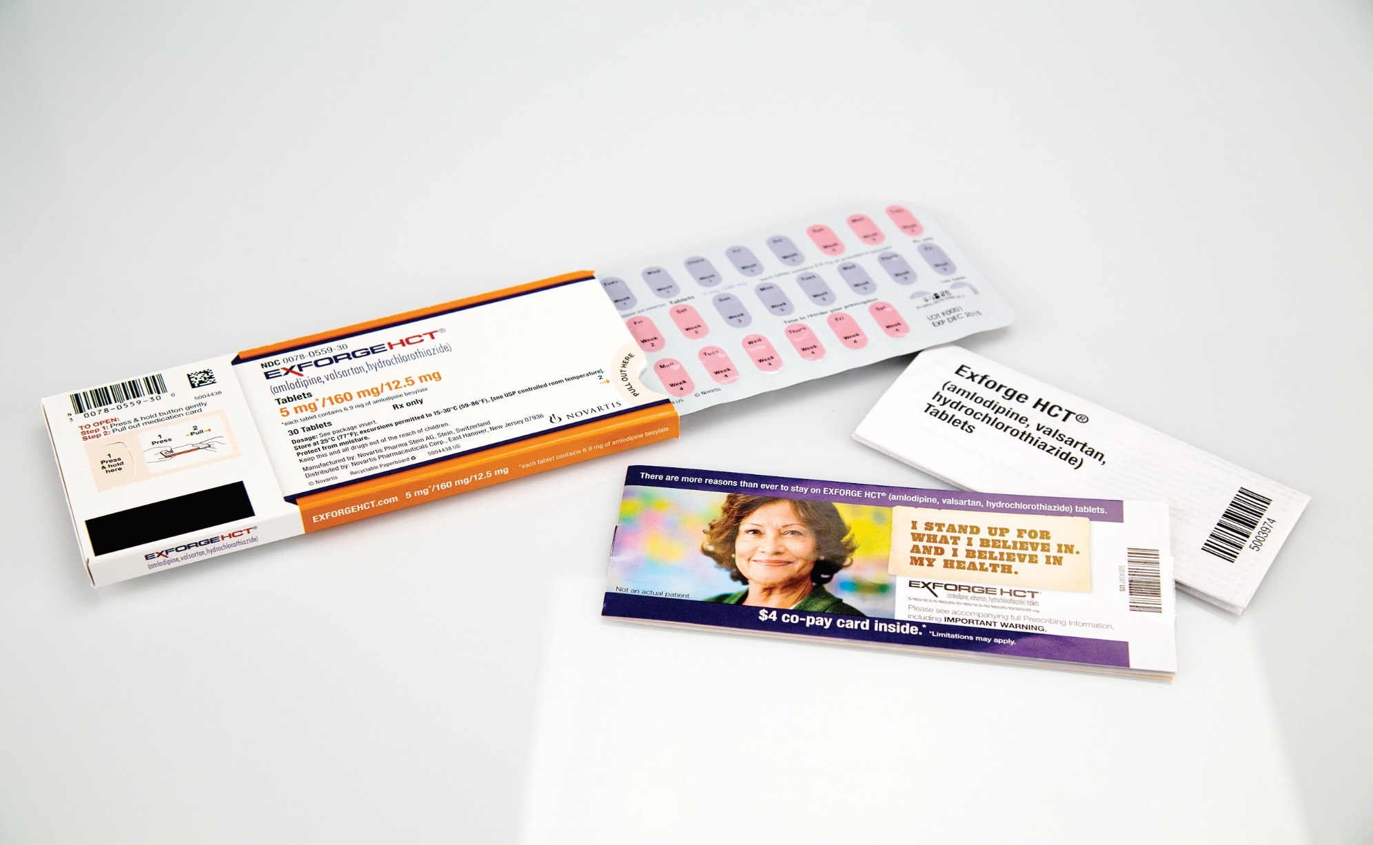 Three items on a white surface. On the left side there is an orange and white box with a barcode and a label on it. Next to it there are two white cards with a picture of a woman's face on them. The card on the right side has a purple and white design with the words "I love you to the moon and back" written in a cursive font. In the center of the image there appears to be a set of pink and white pills. The pills are arranged in a way that they are overlapping each other. The background is plain white.