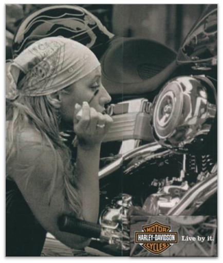 A black and white photograph of a young woman sitting on a Harley-Davidson motorcycle. She is wearing a bandana tied around her head and has long blonde hair. The woman is holding a cigarette in her hand and appears to be deep in thought. The motorcycle is parked in a garage or workshop with various tools and equipment visible in the background. The Harley Davidson logo is visible on the bottom right corner of the image.