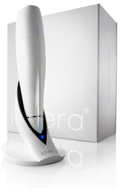 A white-colored device which appears to be an electric shaver placed next to a white box. The device has a sleek and modern design with a curved body and a pointed tip. It has a blue light on the top indicating that it is powered on. The box is rectangular in shape and has the brand name "Ivera" written on it in black letters. The background is plain white making the device and box stand out.