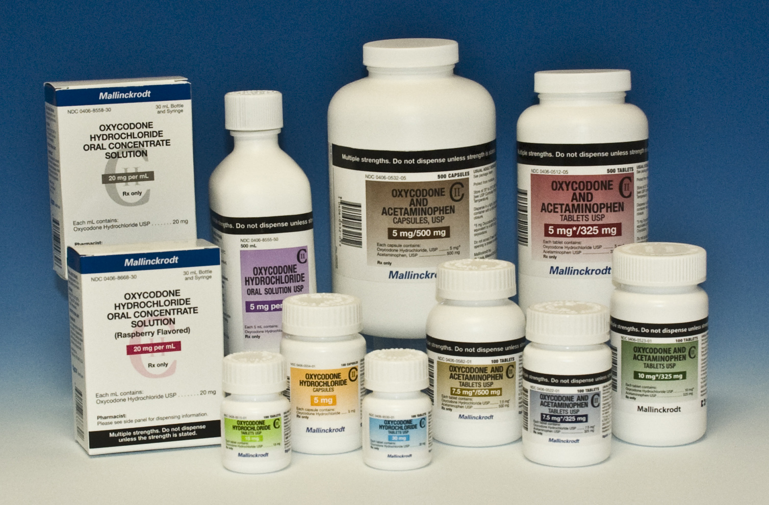 A collection of medical supplies including a white bottle with a label that reads "Oxycodone Acetaminophen" and a blue box with the same label. There are nine small white bottles in total arranged in a scattered manner on a blue background. The bottles appear to be of different sizes and shapes with some being larger and others smaller. The box is rectangular in shape and has a white label with black text. The background is a solid blue color.