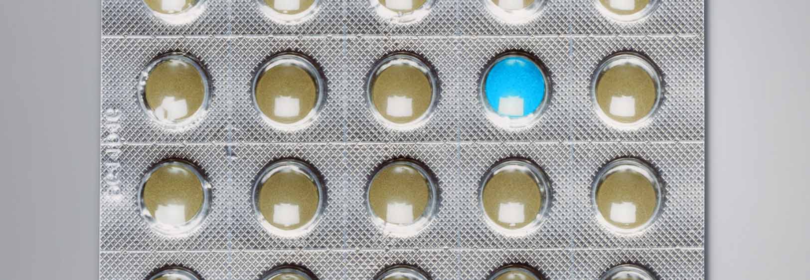 A close-up of a blister pack of pills. The blister pack is rectangular in shape and has a grid-like pattern. The background is white and the pills are a light brown color. The image appears to be taken from a top-down perspective.