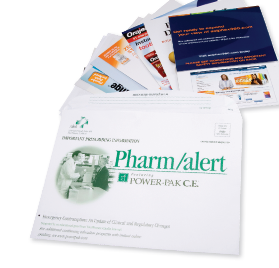 A collection of medical supplies including a white envelope with the words "Pharm/alert Power-Pak C.E." printed on it. The envelope is open revealing the contents inside. On top of the envelope there are several pamphlets and brochures with different designs and colors. The pamphlets appear to be related to the pharmaceutical industry as indicated by the text on the envelope. The background is plain white.